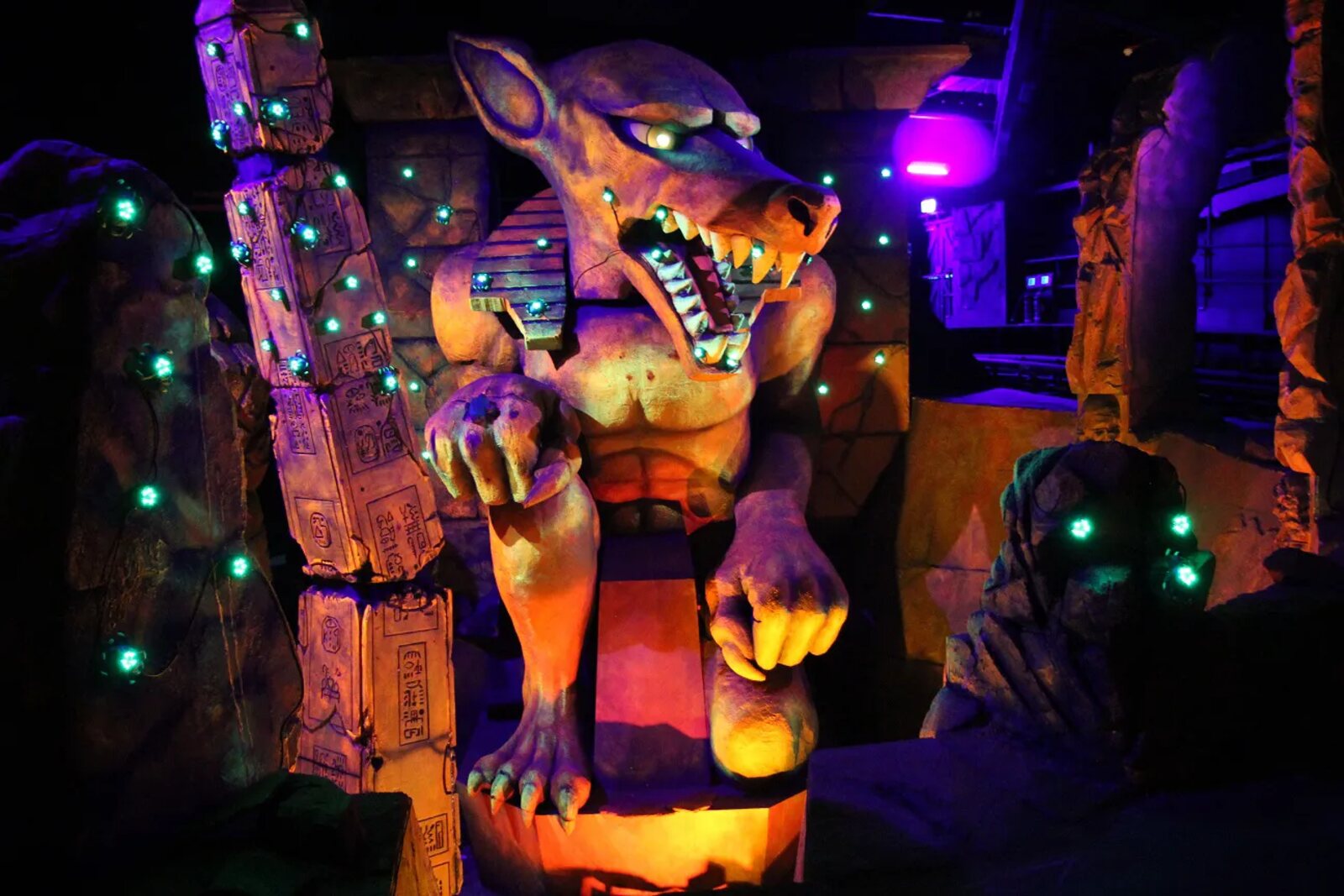 The Anubis figure inside Tomb Blaster at Chessington World of Adventures, lit in orange and purple against the tomb wall