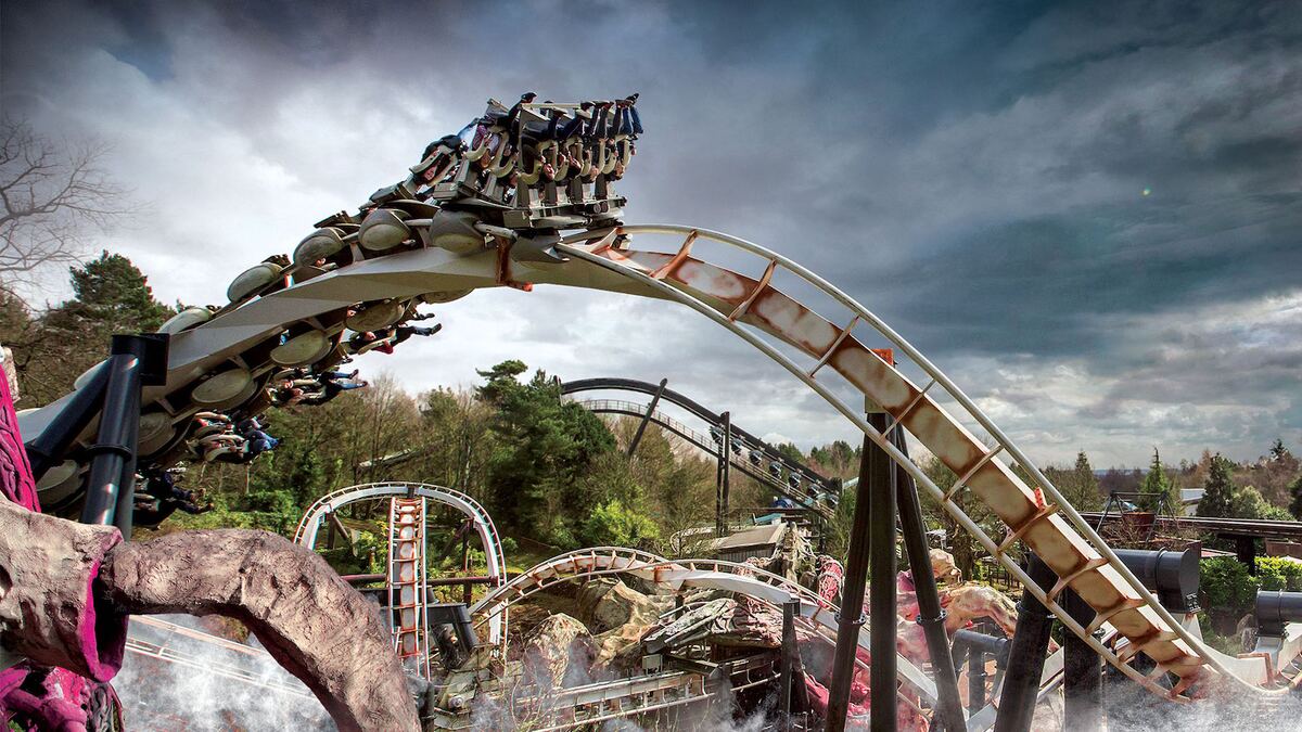 A roller coaster train inverting over its track under a stormy sky, from blooloop's feature